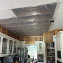 Kitchen ceiling covered in protective plastic tenting with exposed framing during a water damage ceiling repair